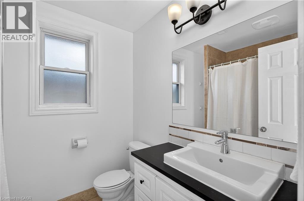 Bathroom with a shower with shower curtain, vanity, and backsplash - 216 Robert Street, Hamilton, ON - Indoor Photo Showing Bathroom
