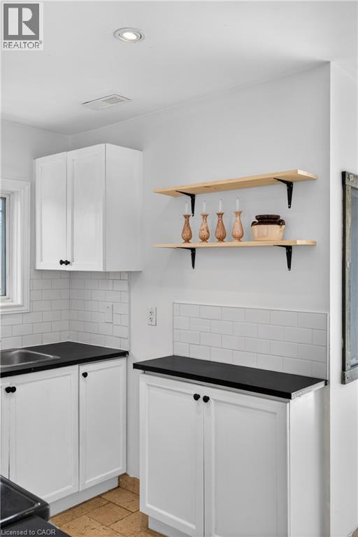 Kitchen with stone tile flooring, dark countertops, white cabinets, and recessed lighting - 216 Robert Street, Hamilton, ON - Indoor Photo Showing Kitchen