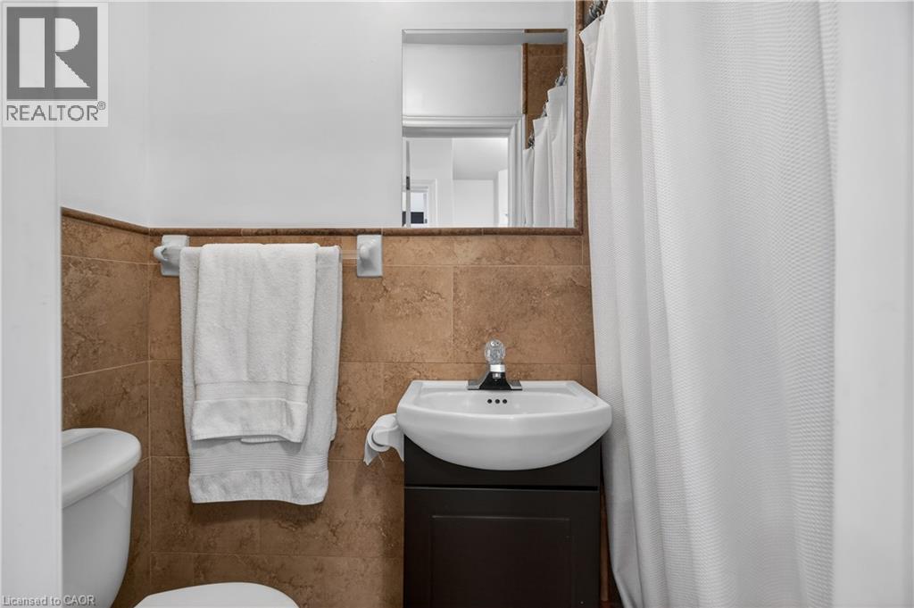 Full bath featuring a shower with curtain, vanity, and tile walls - 216 Robert Street, Hamilton, ON - Indoor Photo Showing Bathroom