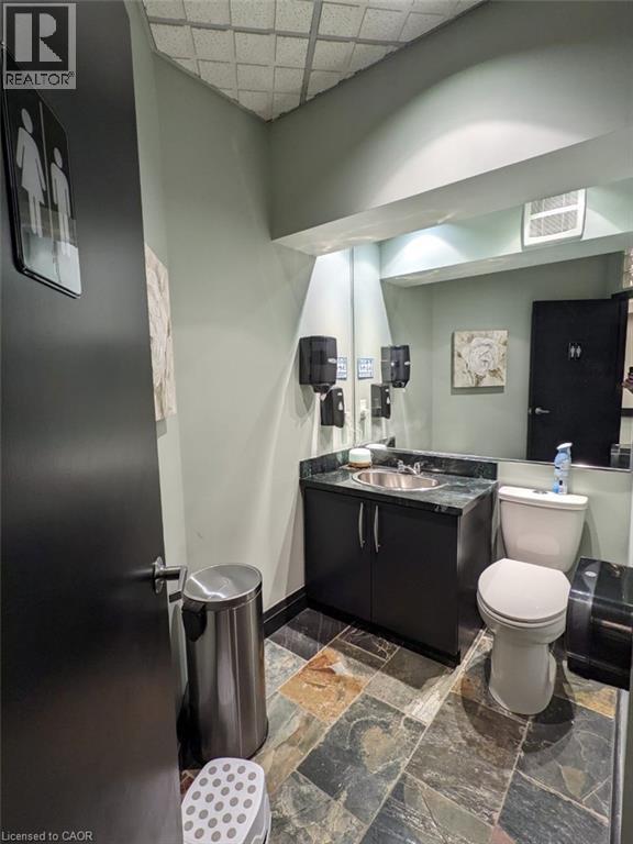 Half bathroom featuring vanity, stone tile flooring, and a paneled ceiling - 14 Duke Street, Hamilton, ON - Indoor