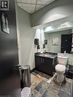 Half bathroom featuring vanity, stone tile flooring, and a paneled ceiling -