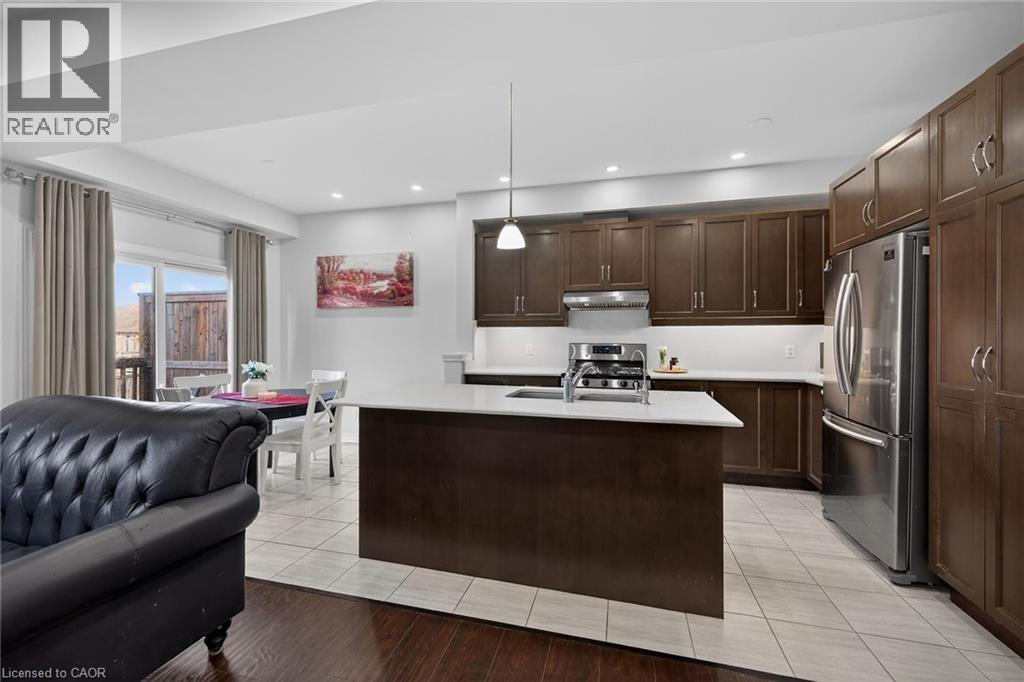 Kitchen featuring a kitchen island with sink, stainless steel appliances, dark wood finish cabinets, decorative light fixtures, and open floor plan - 80 Severino Circle, Smithville, ON - Indoor Photo Showing Kitchen With Double Sink