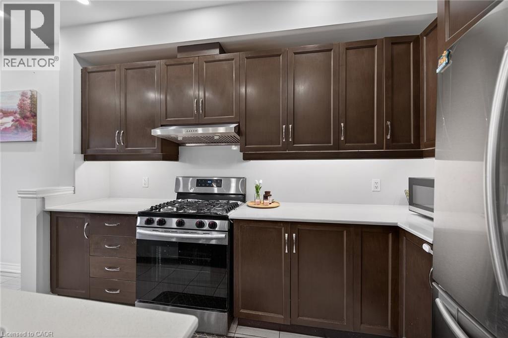 Kitchen with stainless steel appliances, dark wood finish cabinetry, and light countertops - 80 Severino Circle, Smithville, ON - Indoor Photo Showing Kitchen