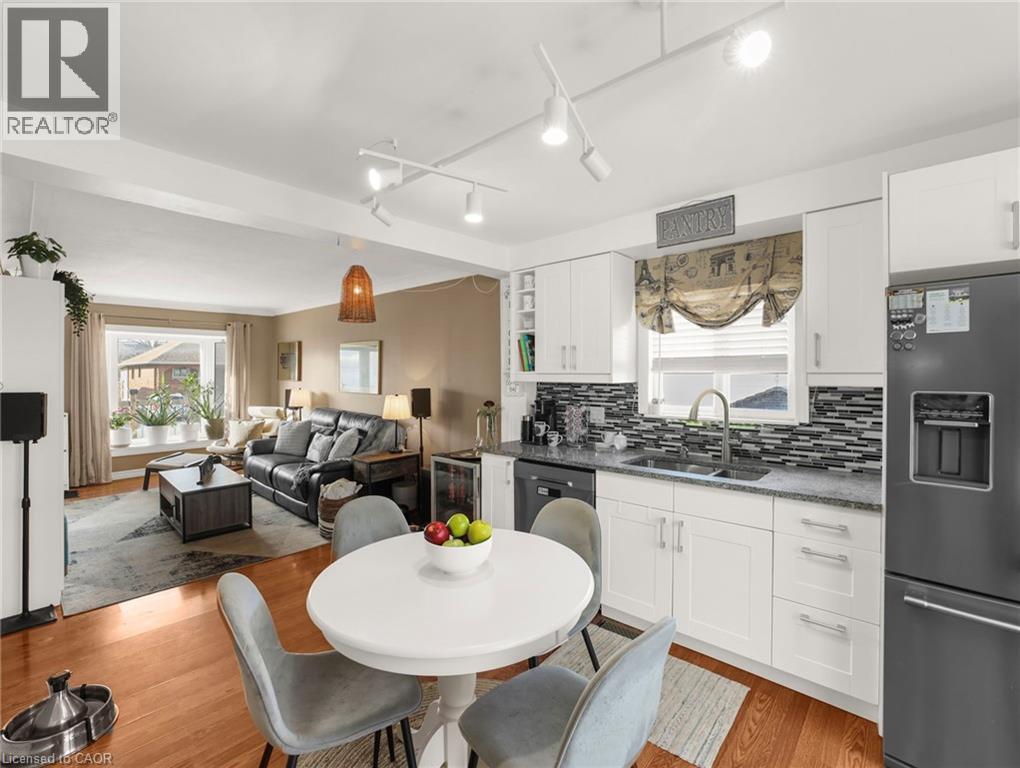 Kitchen with fridge with ice dispenser, white cabinetry, open floor plan, dark stone counters, and track lighting - 420 Waverly Street, Hamilton, ON - Indoor Photo Showing Other Room