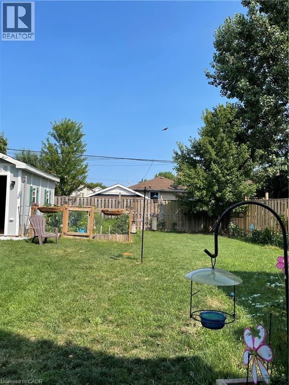 The property features a spacious backyard with a well-maintained lawn and a wooden fence - 420 Waverly Street, Hamilton, ON - Outdoor
