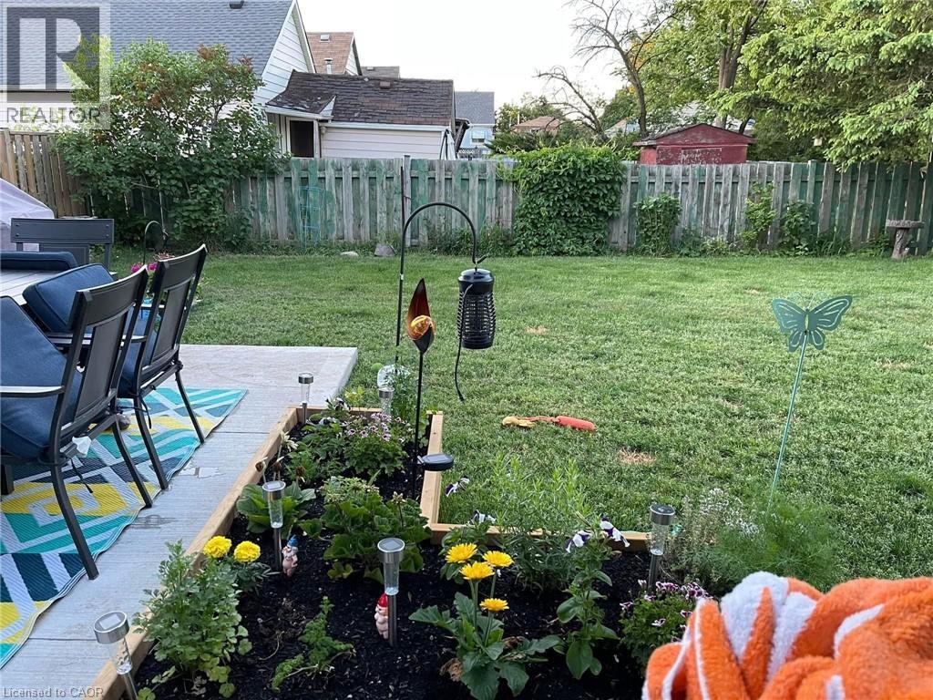 The property features a spacious lawn area, a paved patio, and a raised garden bed with various plantings - 420 Waverly Street, Hamilton, ON - Outdoor