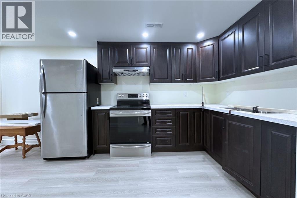 Kitchen featuring stainless steel appliances, light countertops, light wood-type flooring, recessed lighting, and dark wood finish cabinets - 59 Windrush Trail S Unit# B, Kitchener, ON - Indoor Photo Showing Kitchen