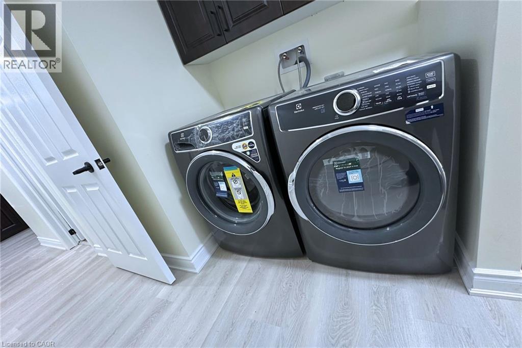 Laundry room featuring light wood-style flooring, washing machine and dryer, and cabinet space - 59 Windrush Trail S Unit# B, Kitchener, ON - Indoor Photo Showing Laundry Room