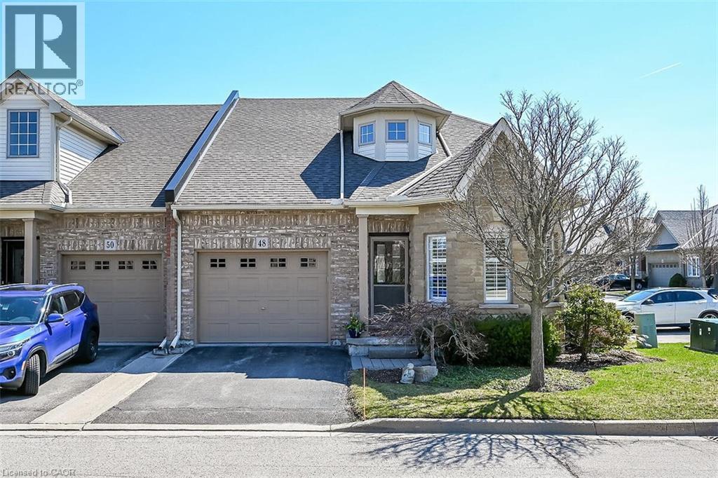 French provincial home featuring a shingled roof, driveway, a garage, a front lawn, and stone siding - 48 Hallmark Trail, Hamilton, ON - Outdoor