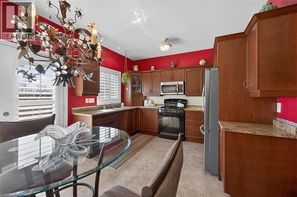 Kitchen featuring stainless steel appliances, glass insert cabinets, light countertops, and tasteful backsplash - 48 Hallmark Trail, Hamilton, ON - Indoor