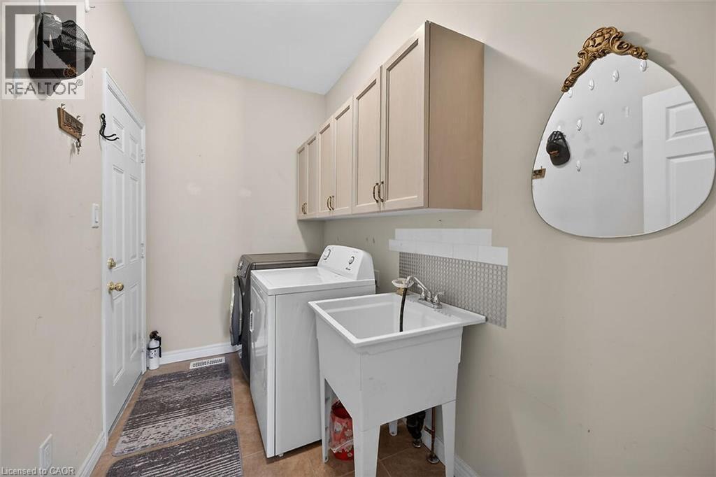 Laundry area featuring cabinet space, washer and clothes dryer, and light tile patterned flooring - 48 Hallmark Trail, Hamilton, ON - Indoor Photo Showing Laundry Room