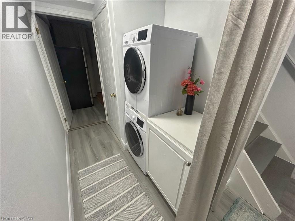 Laundry area with light wood finished floors and stacked washer / drying machine - 206A Springfield Crescent Unit# Lower, Waterloo, ON - Indoor Photo Showing Laundry Room