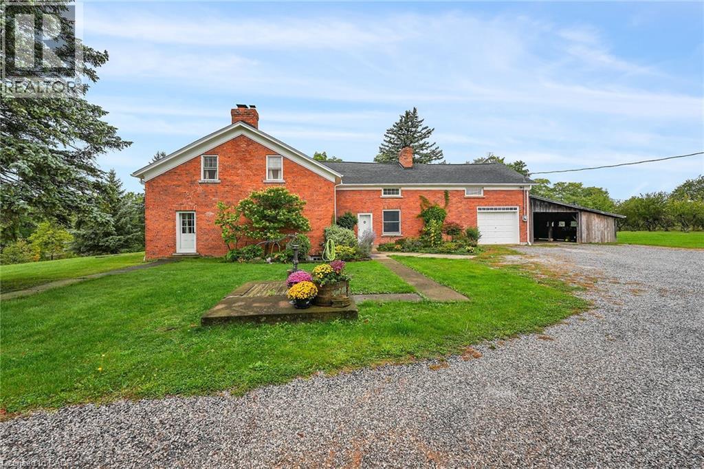 View of front of home featuring a chimney, driveway, a garage, a front lawn, and brick siding - 2432 Seburn Road, Fonthill, ON - Outdoor