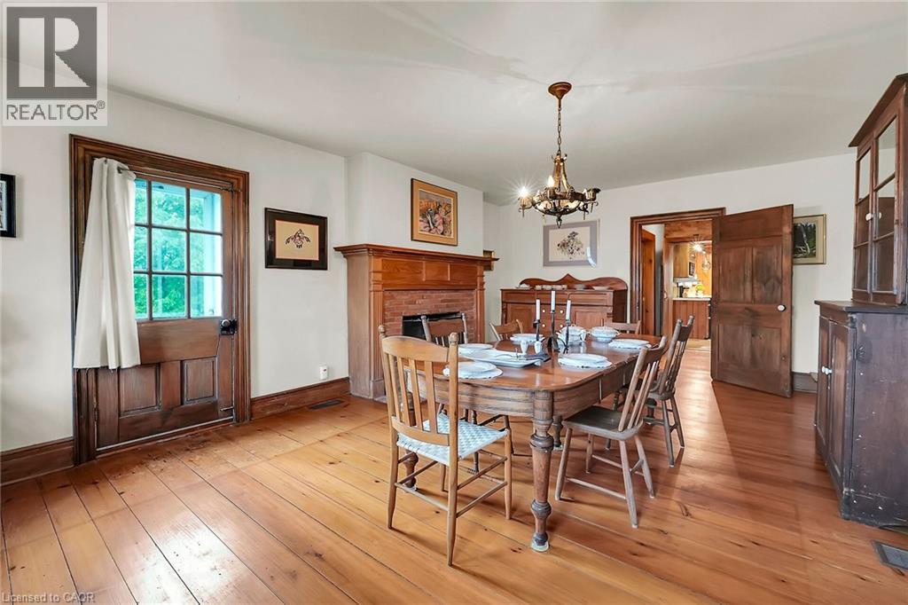 Dining space featuring suspended lighting, light wood-style flooring, and a brick fireplace - 2432 Seburn Road, Fonthill, ON - Indoor Photo Showing Dining Room With Fireplace