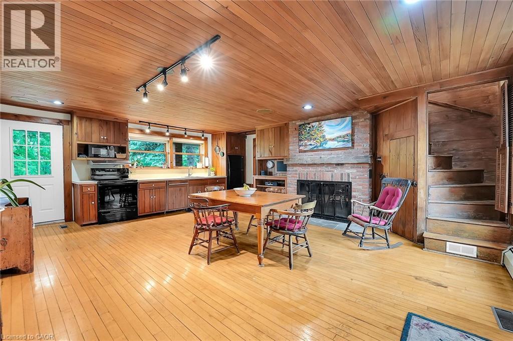 Dining area featuring rail lighting, light wood finished floors, a fireplace, wood ceiling, and wooden walls - 2432 Seburn Road, Fonthill, ON - Indoor With Fireplace