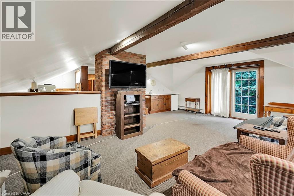 Living area featuring carpet flooring, vaulted ceiling with beams, a baseboard radiator, and a fireplace - 2432 Seburn Road, Fonthill, ON - Indoor