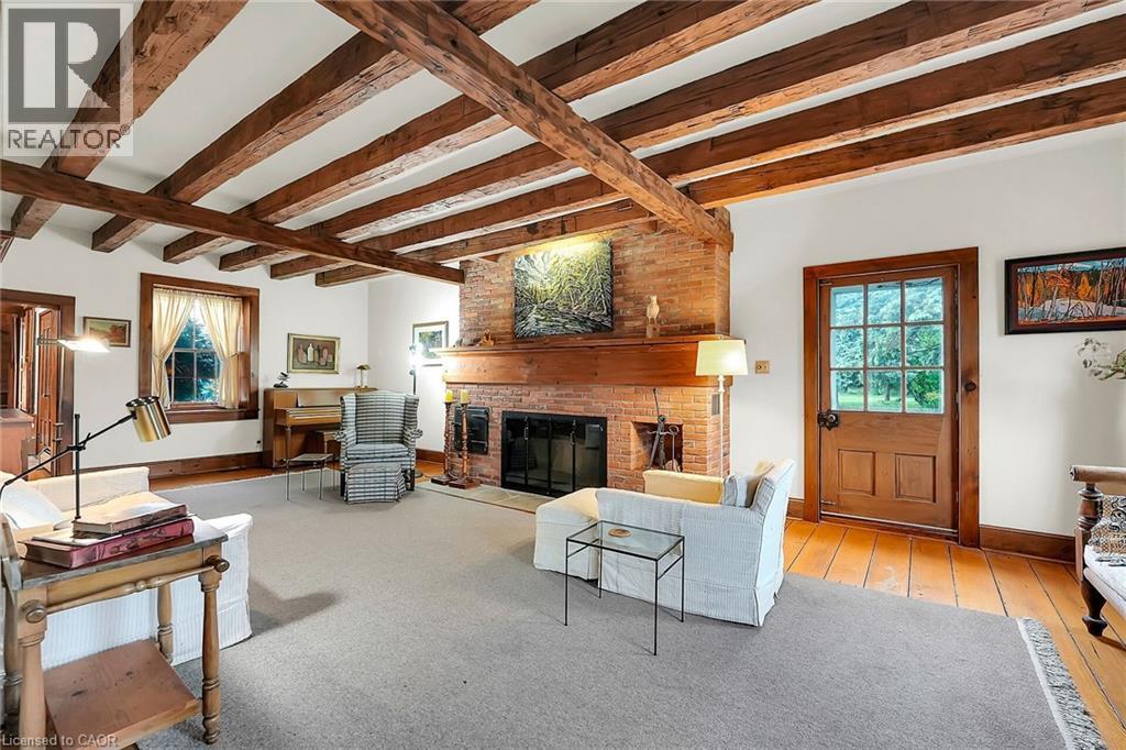 Living room with a brick fireplace, beam ceiling, and light wood finished floors - 2432 Seburn Road, Fonthill, ON - Indoor Photo Showing Living Room With Fireplace