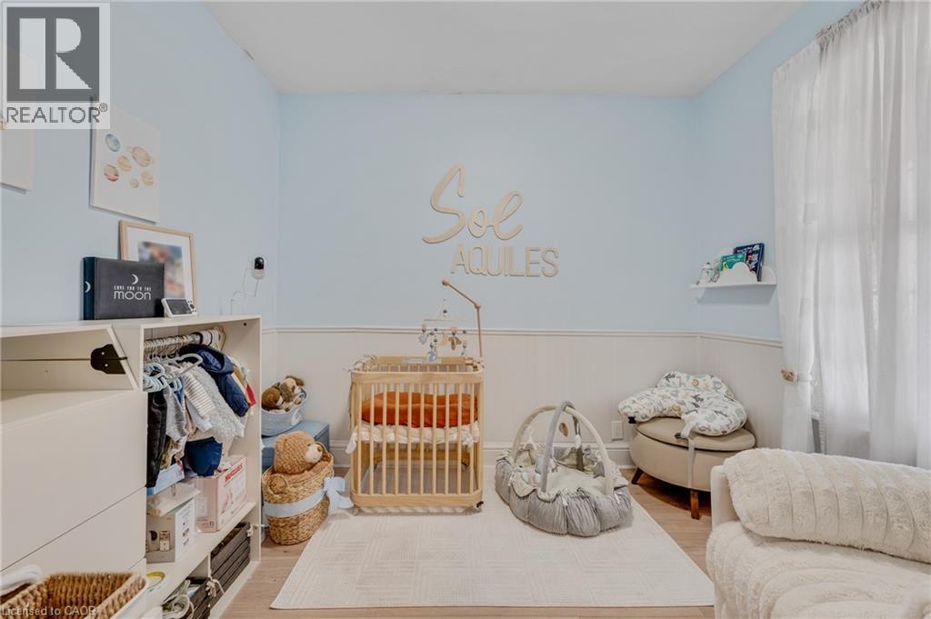 Bedroom with a crib, light wood-style flooring, and wainscoting - 6 Ben Lomond Place, Hamilton, ON - Indoor