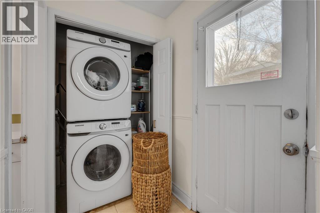 Laundry area featuring stacked washer / drying machine and light tile patterned floors - 6 Ben Lomond Place, Hamilton, ON - Indoor Photo Showing Laundry Room