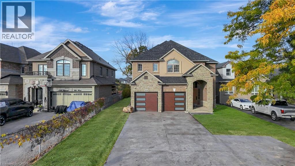 View of front of property featuring stone siding, a front lawn, driveway, and an attached garage - 254 Rymal Road W, Hamilton, ON - Outdoor With Facade
