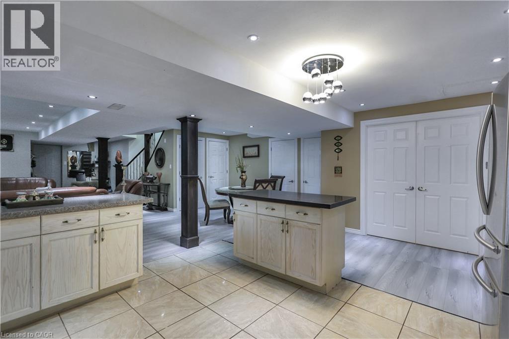 Kitchen with light wood finish cabinets, open floor plan, freestanding refrigerator, dark countertops, and light tile patterned flooring - 254 Rymal Road W, Hamilton, ON - Indoor