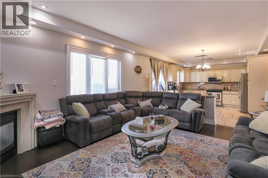 Living area featuring suspended lighting, wood finished floors, and a glass covered fireplace - 254 Rymal Road W, Hamilton, ON - Indoor Photo Showing Living Room With Fireplace
