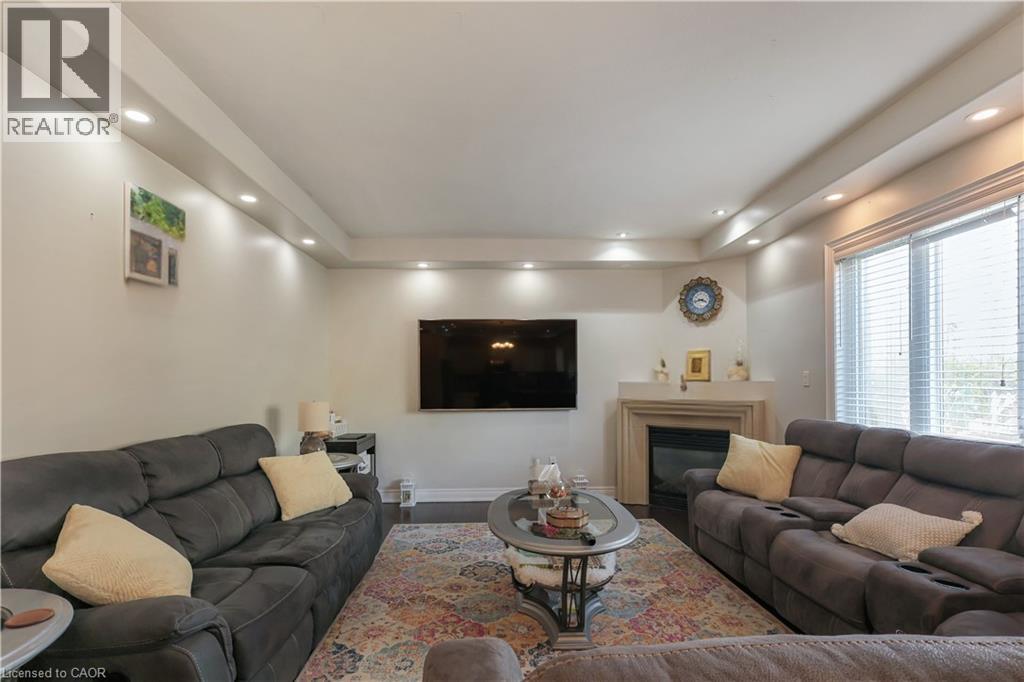 Living area featuring a raised ceiling, a glass covered fireplace, recessed lighting, and wood finished floors - 254 Rymal Road W, Hamilton, ON - Indoor Photo Showing Living Room With Fireplace