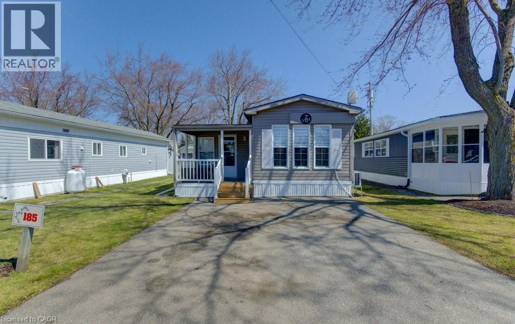 Manufactured / mobile home featuring a front lawn, driveway, and a wooden deck - 580 Beaver Creek Road Unit# 185, Waterloo, ON - Outdoor