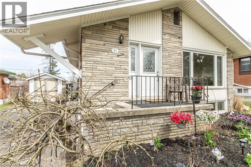 View of home's exterior featuring stone siding, a storage unit, and a porch - 11 Carwyn Crescent, Hamilton, ON - Outdoor With Deck Patio Veranda