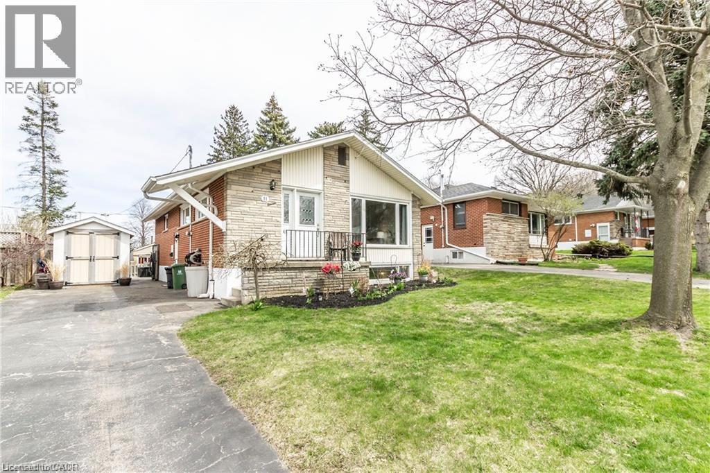 View of front of home with a shed, stone siding, asphalt driveway, and a front yard - 11 Carwyn Crescent, Hamilton, ON - Outdoor With Facade