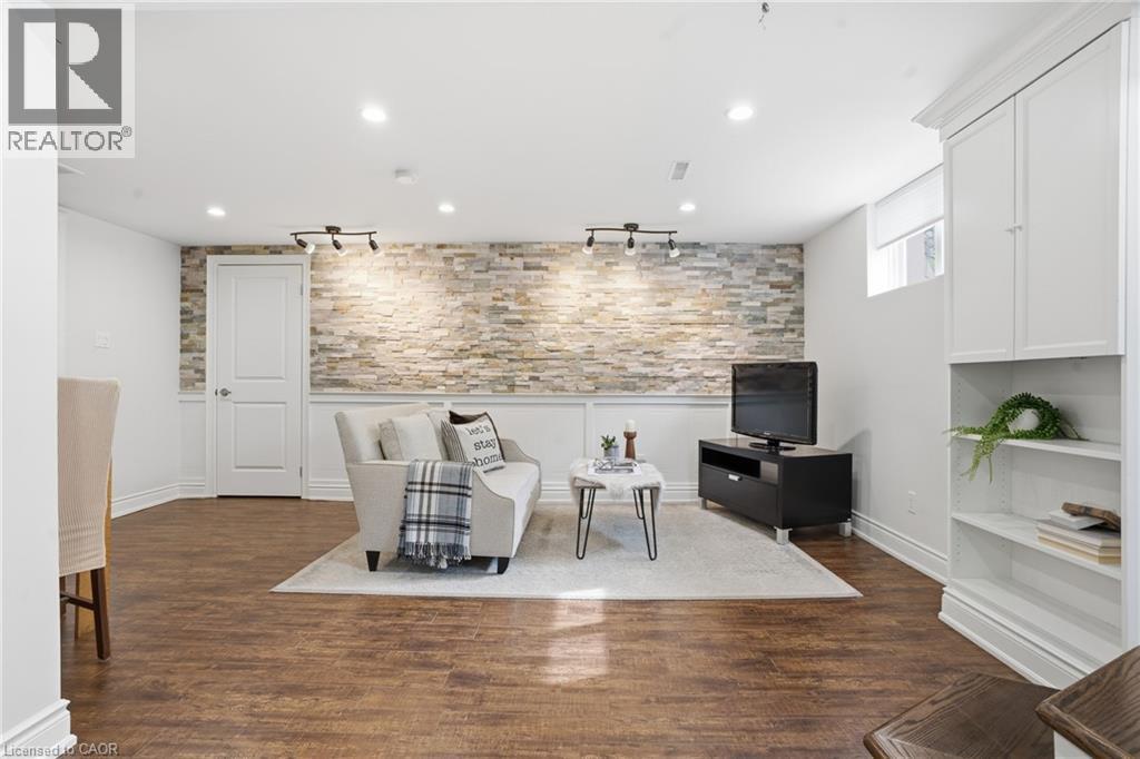Living room features hardwood flooring, an elegant chandelier, stylish tray ceiling & built in featureornamental molding - 208 East 44Th Street, Hamilton, ON - Indoor