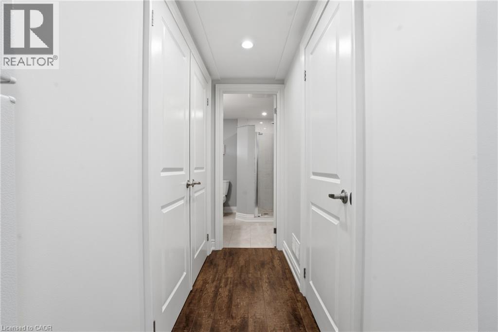 Lower level hallway leads to full bathroom with recessed lighting and laminate wood floors. Utility room is spacious & large double closet is great for added storage. - 208 East 44Th Street, Hamilton, ON - Indoor Photo Showing Other Room