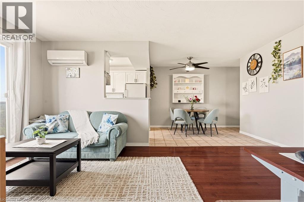 Living area with medium vinyl wood-type flooring, a wall mounted air conditioner, and ceiling fan - 2373 E King Street E Unit# 45, Hamilton, ON - Indoor Photo Showing Living Room