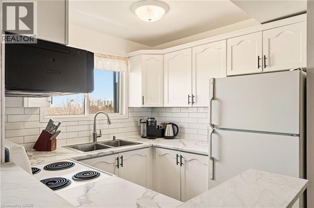 Kitchen featuring white appliances, white cabinetry, tasteful backsplash, and light countertops - 2373 E King Street E Unit# 45, Hamilton, ON - Indoor Photo Showing Kitchen With Double Sink