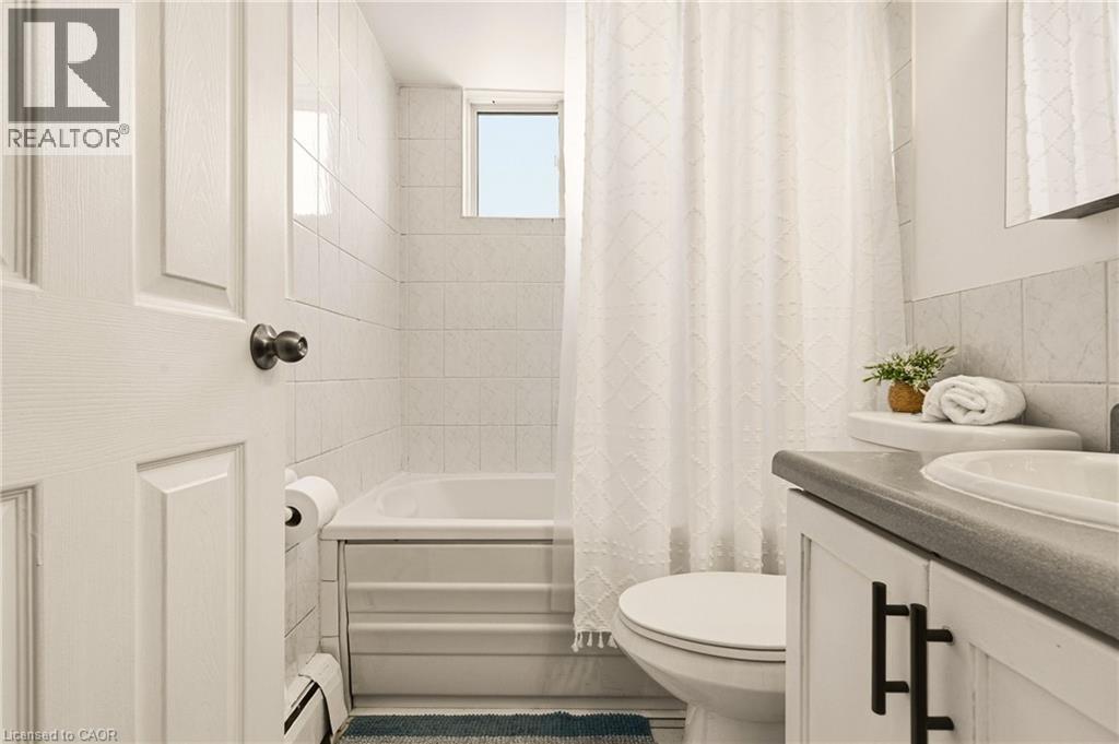 Bathroom with vanity, shower / bath combo with shower curtain, tile walls - 2373 E King Street E Unit# 45, Hamilton, ON - Indoor Photo Showing Bathroom