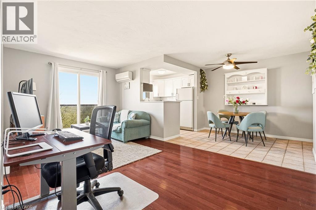 Open concept office area/living room with medium vinyl wood-style flooring, ceiling fan, and a wall mounted air conditioner - 2373 E King Street E Unit# 45, Hamilton, ON - Indoor