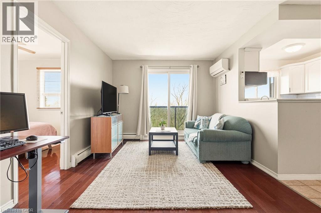 Living area with medium vinyl wood-type flooring and a baseboard heating unit, wall mounted air conditioner, sliding doors to balcony - 2373 E King Street E Unit# 45, Hamilton, ON - Indoor