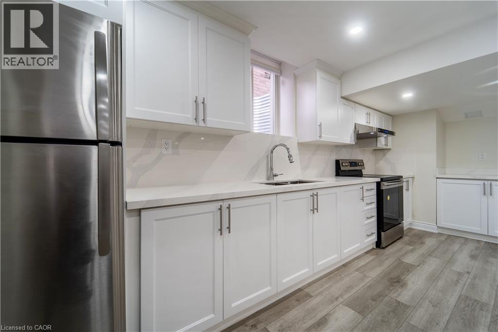 Kitchen with stainless steel appliances, white cabinets, light wood-type flooring, backsplash, and recessed lighting - 150 Goodwin Crescent Unit# Bsmt, Milton, ON - Indoor Photo Showing Kitchen