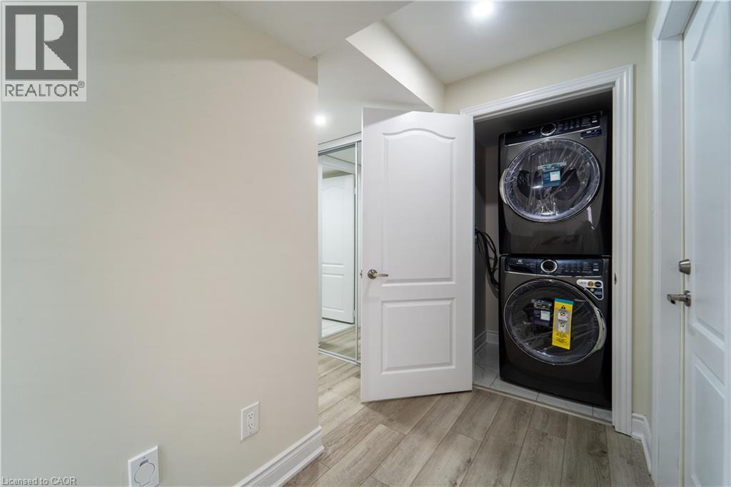 Laundry area featuring light wood-type flooring and stacked washer and dryer - 150 Goodwin Crescent Unit# Bsmt, Milton, ON - Indoor Photo Showing Laundry Room