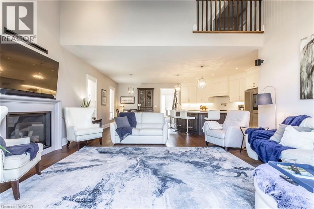 Living area featuring a glass covered fireplace, dark wood finished floors, and a high ceiling - 72 Pond View Gate, Waterdown, ON - Indoor Photo Showing Living Room With Fireplace