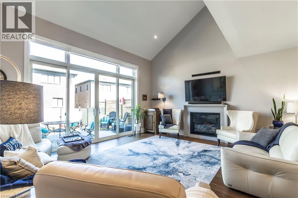 Living room with lofted ceiling, a glass covered fireplace, wood finished floors, and recessed lighting - 72 Pond View Gate, Waterdown, ON - Indoor Photo Showing Living Room With Fireplace