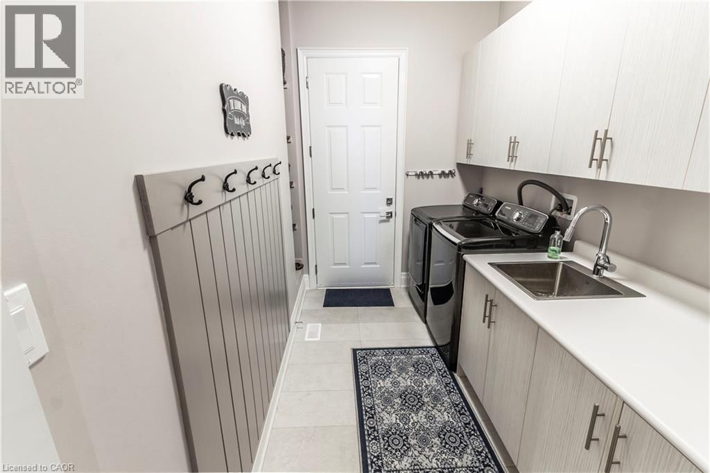 Laundry area featuring cabinet space, light tile patterned floors, and washer and dryer - 72 Pond View Gate, Waterdown, ON - Indoor Photo Showing Kitchen With Double Sink