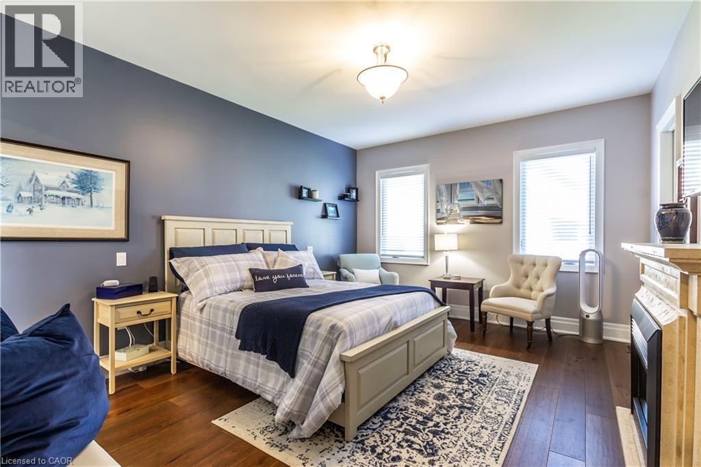 Bedroom featuring dark wood-type flooring and a fireplace - 72 Pond View Gate, Waterdown, ON - Indoor Photo Showing Bedroom