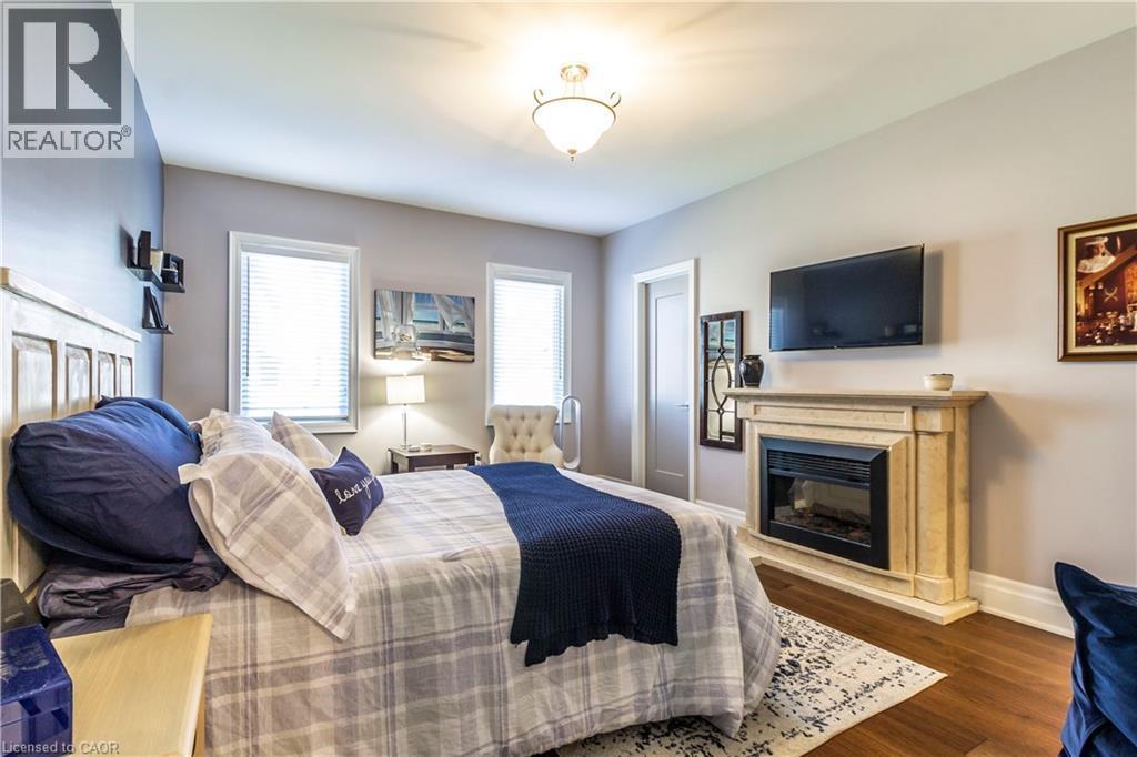 Bedroom featuring a glass covered fireplace and dark wood finished floors - 72 Pond View Gate, Waterdown, ON - Indoor With Fireplace