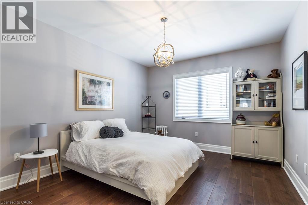 Bedroom featuring dark wood finished floors and hanging lights - 72 Pond View Gate, Waterdown, ON - Indoor Photo Showing Bedroom