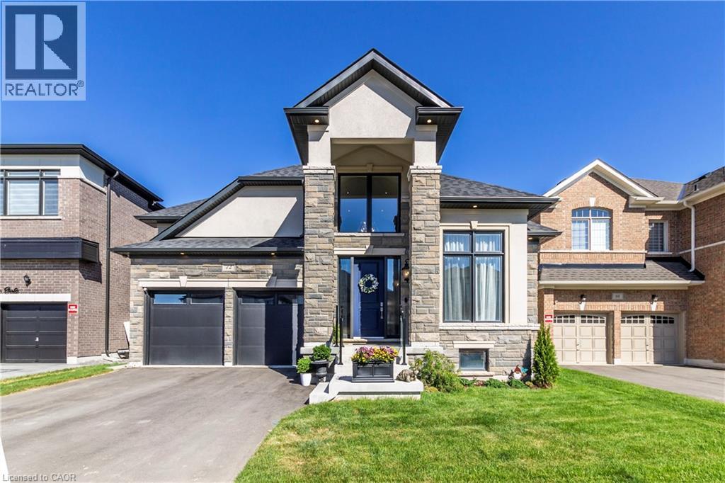 View of front of house featuring stone siding, driveway, a front yard, and stucco siding - 72 Pond View Gate, Waterdown, ON - Outdoor With Facade