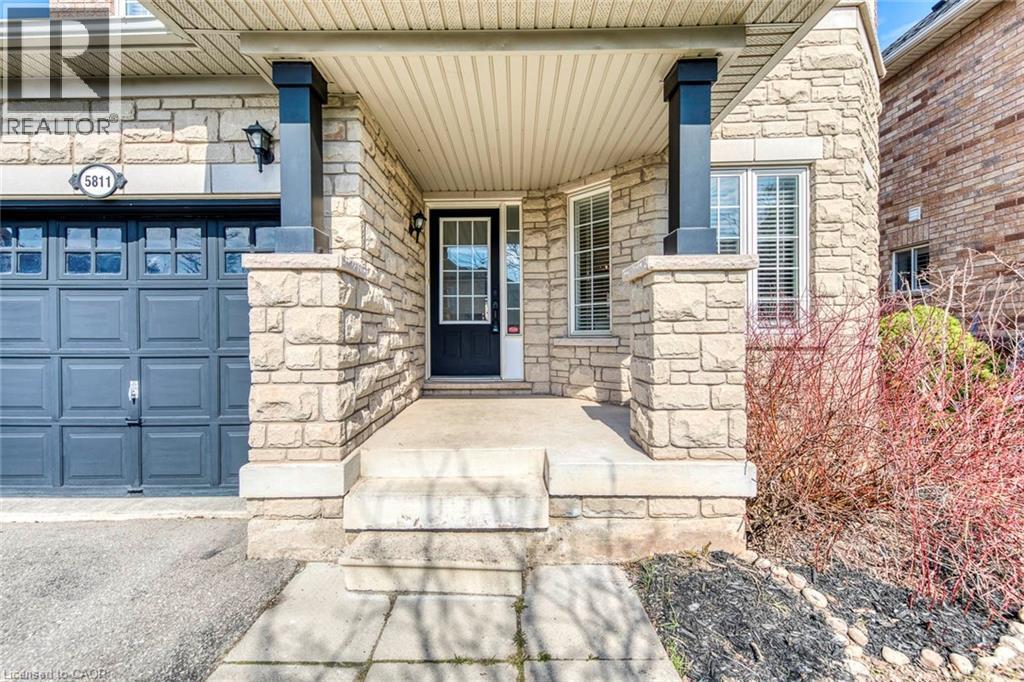 Entrance to property featuring stone siding, a porch, and a garage - 5811 Page Crescent, Burlington, ON - Outdoor With Facade