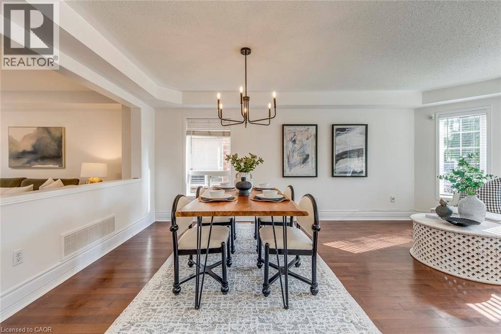 Dining space featuring hanging lights, dark wood-style flooring, a textured ceiling, and healthy amount of natural light - 5811 Page Crescent, Burlington, ON - Indoor