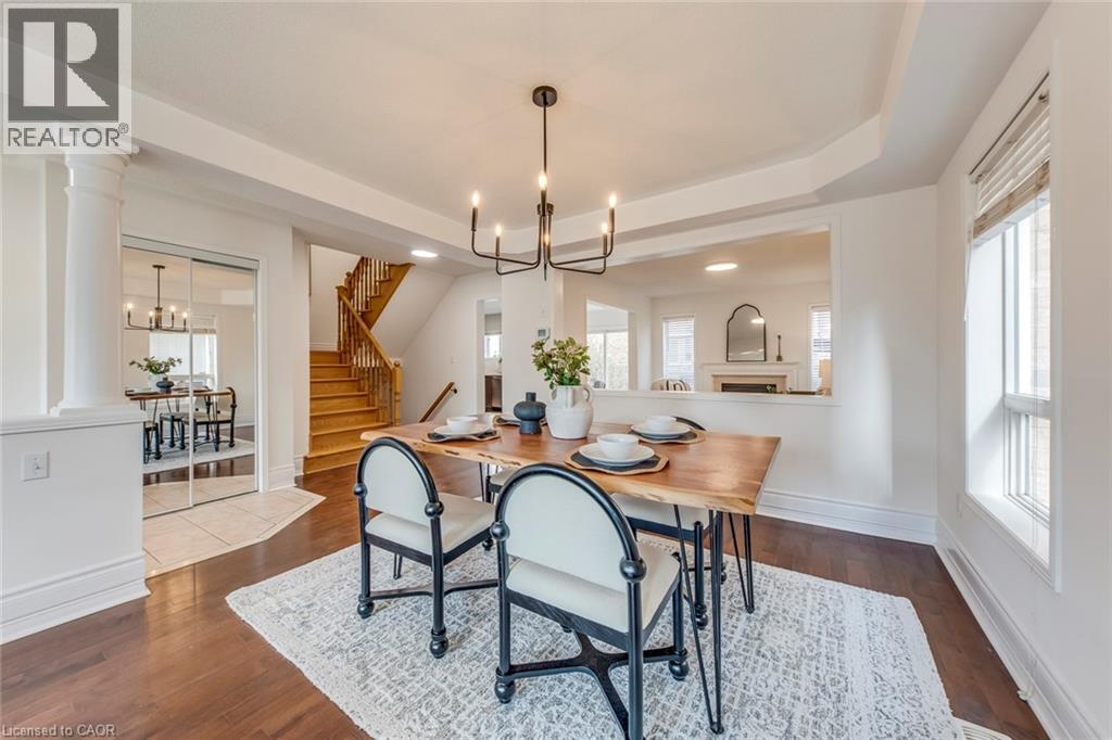 Dining room with suspended lighting, dark wood-style floors, decorative columns, and a tray ceiling - 5811 Page Crescent, Burlington, ON - Indoor Photo Showing Dining Room
