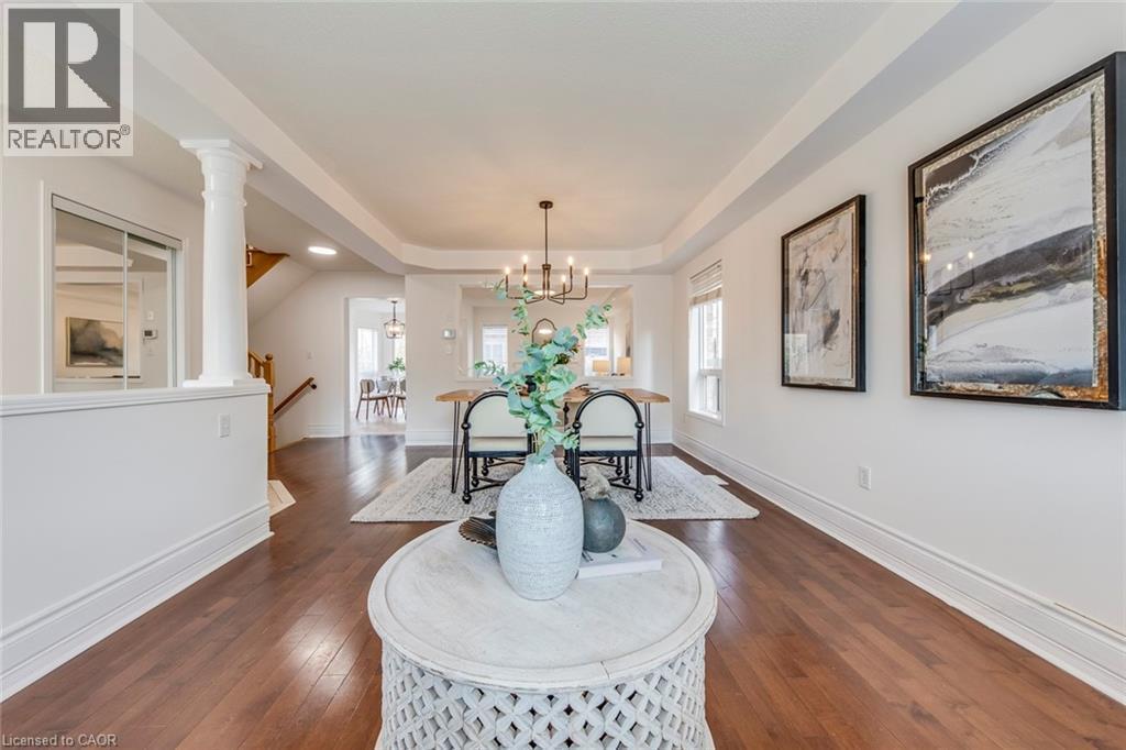Dining space with a raised ceiling, dark wood finished floors, a chandelier, and decorative columns - 5811 Page Crescent, Burlington, ON - Indoor